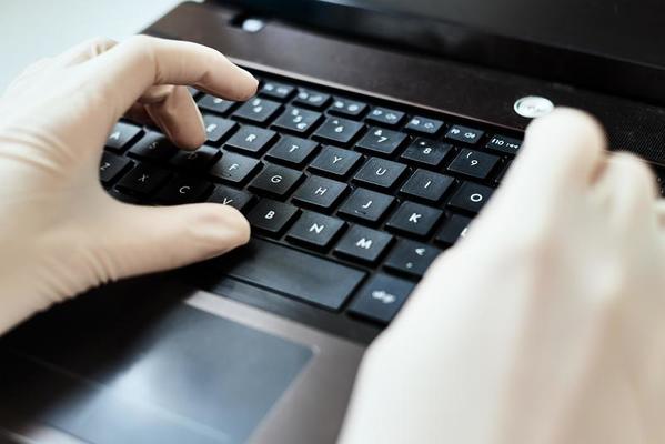 Hands in gloves typing on the laptop keyboard. Virus protection concept