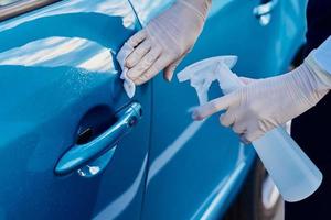 Woman disinfects a car door handle with an antibacterial spray. Car washing photo