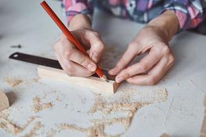 Carpenter hands taking measurement with a pencil of wooden plank. photo