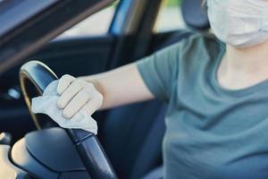 Woman cleaning car steering wheel with a disinfection spray photo