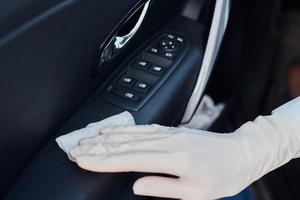 mujer limpiando el interior del coche. mano con una toallita antibacteriana desinfectar el coche foto
