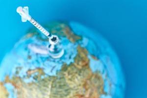 Medical syringe and ampoule with a medicine against Earth globe photo