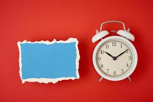 White vintage classic alarm clock with bells and empty torn paper sheet photo