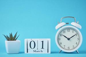 despertador retro blanco con campanas y bloques de calendario de madera con fecha 1 de marzo foto