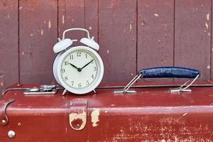 Alarm clock and brown retro suitcase closeup. Time running out concept photo