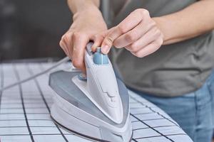 mujer planchando ropa en la tabla de planchar con plancha moderna foto