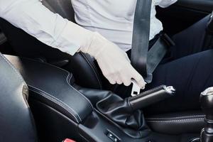 Driver in rubber gloves fastens seat belt in the car photo