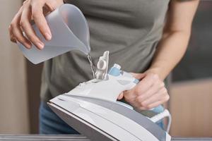 Woman load water in the iron. Prepare iron for ironing photo