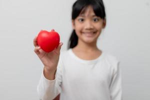 retrato de una niña asiática con un cartel de corazón rojo en el fondo blanco foto