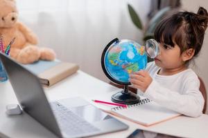 Asian little girl is learning the globe model, concept of save the world and learn through play activity for kid education at home. photo