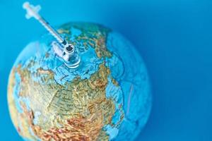 Medical syringe and ampoule with a medicine against Earth globe photo