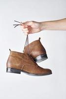 Female hand holding brown leather boots on the shoeleces photo