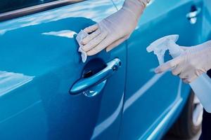 Woman disinfects a car door handle with an antibacterial spray. Car washing photo