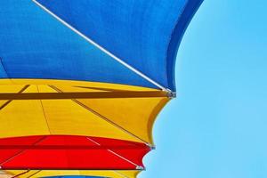 sombrillas de playa de colores contra el cielo azul en el día de verano foto