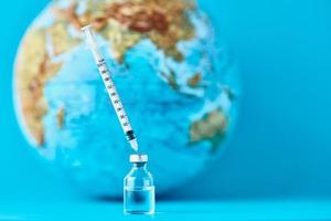 Medical syringe and ampoule with a medicine against Earth globe. photo