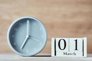 Alarm clock and wooden block calendar with date 1st march on the table photo