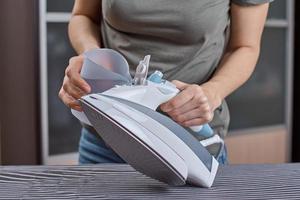 Woman load water in the iron. Prepare iron for ironing photo