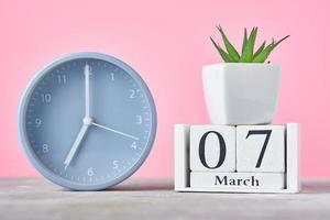 Wooden block calendar with date 7 march, alarm clock photo