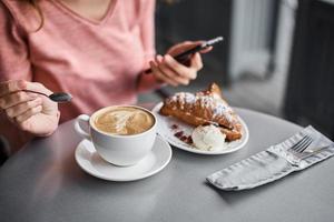 Woman have breakfast in caffe and using smartphone photo