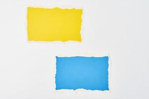 Two ripped color paper torn edge sheets on the white background photo