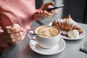 Woman have breakfast in caffe and using smartphone photo