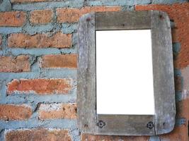 Rustic wooden photo frame hanging on old brick wall with empty place for text or image