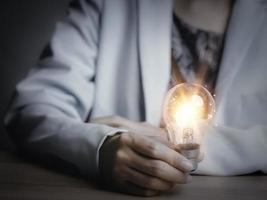 Businesswoman holding a light bulb, Creative new idea. Innovation, brainstorming, solution and inspiration concepts. imagination, creative thinking problem solving. photo