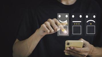 teléfono inteligente para seleccionar el icono de satisfacción del cliente de la cara sonriente para la evaluación del cliente y el concepto de retroalimentación del servicio después del uso. foto
