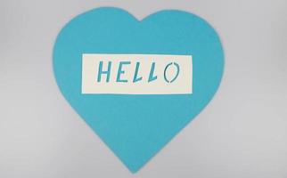 World Congratulations Day. The day of winning friends. The word hello and a blue heart cut out of paper on a white background. The concept of communication photo