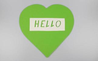 World Congratulations Day. The day of winning friends. The word hello and a green heart cut out of paper on a white background. The concept of communication photo