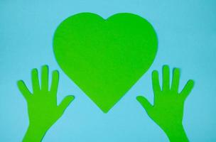 Paper green hands support a paper green heart. The concept of environmental protection photo