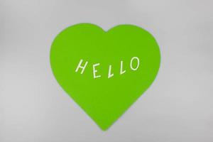 World Congratulations Day. The day of winning friends. The word hello and a green heart cut out of paper on a white background. The concept of communication photo