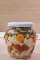 Jar with pickles,cauliflower, carrots, bell peppers, garlic and celery photo