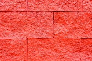 Texture of bright red large large rectangular convex stone bricks. The background photo