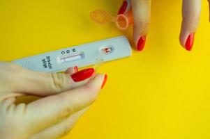 coronavirus test on a yellow, bright background. medical analysis. test strip to assess the presence of IgG and IgM antibodies. girl with red manicure adds saline to the strip photo