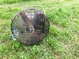 Large round powerful industrial professional metal iron fan with louvres for injecting air into the balloon against the background of green grass photo