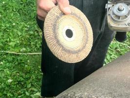 A man holds in his hand a disk of a circle used for a grinding machine for grinding and polishing surfaces from various materials wood, metal, plastic, stone photo