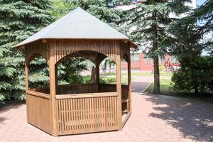 Wooden brown pavilion for rest on a background of green fir trees photo