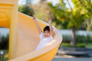 Child playing on outdoor playground. Kids play on school or kindergarten yard. Active kid on colorful slide and swing. Healthy summer activity for children. Little girls climbing outdoors. photo