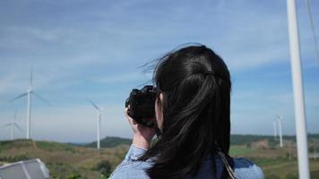vista trasera de una mujer disparando una foto del parque eólico durante el viaje video