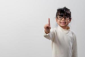 education, school, and imaginary screen concept - Asian little girl pointing in the air or imaginary screen photo