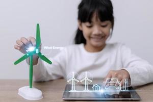 Asian little girl Works with Wind Turbine Prototype virturl, Learning about Environment and Renewable Energy. Children Working on Technology. wind energy concept. STEM Education photo