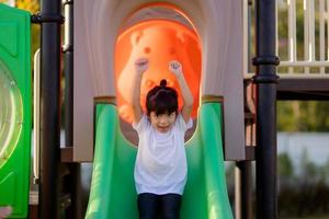 Child playing on outdoor playground. Kids play on school or kindergarten yard. Active kid on colorful slide and swing. Healthy summer activity for children. Little girls climbing outdoors. photo