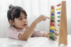 una joven asiática linda está usando el ábaco con cuentas de colores para aprender a contar en casa foto