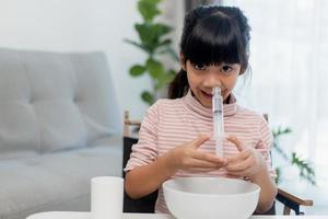 Little asian girl saline nasal wash nose at home. photo