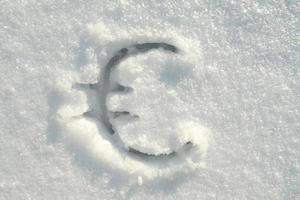 signo del euro escrito en nieve pura en un soleado día de invierno. vista superior. foto