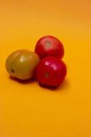 three tomatoes isolated on yellow photo