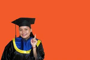 Pointing up. A smiling young female student in a graduation gown. Education, graduation and student life concept. got an idea. photo