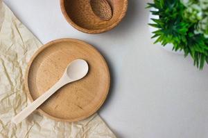 Wooden utensils on the kitchen table. Round wooden plates, a spoons, a green plant. The concept of serving, cooking, interior details. Top view photo