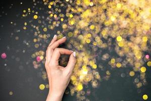 Woman hand with golden bokeh lights on background photo